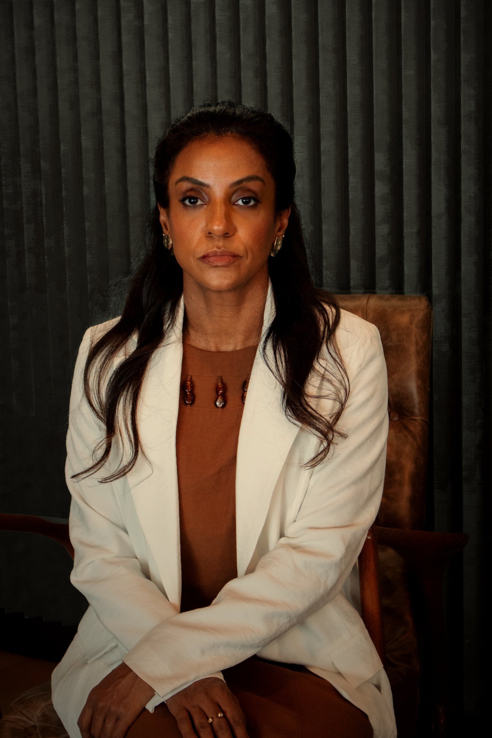 Dra. Marcela Araujo Silva, de blazer branco, sentada, olhando para a câmera
